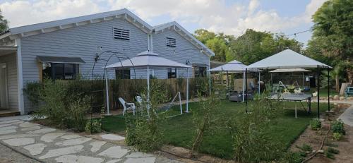 a yard with chairs and umbrellas in front of a house at רגע ערבה in ‘En Yahav