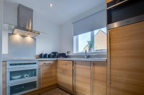 a kitchen with wooden cabinets and a sink and a window at Stay Yorkshire Hamilton Mews Apartment in Doncaster