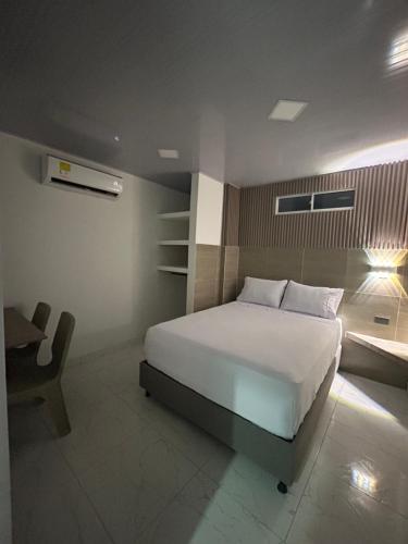 a bedroom with a large white bed and a desk at Hotel Brisas del Mar in Santa Marta