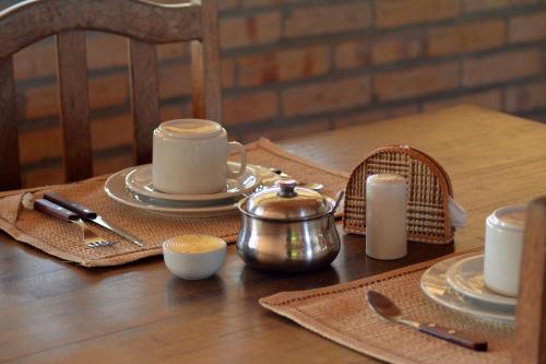 a wooden table with plates and cups and a tea kettle at Pousada Oceania in Taíba
