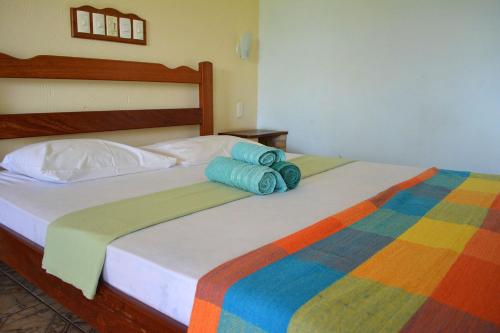 a bed with colorful blankets and pillows on it at Pousada Oceania in Taíba