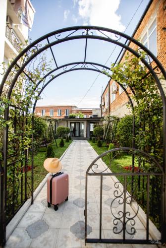 an arched gate with a suitcase on a walkway at Central Inn in Kutaisi