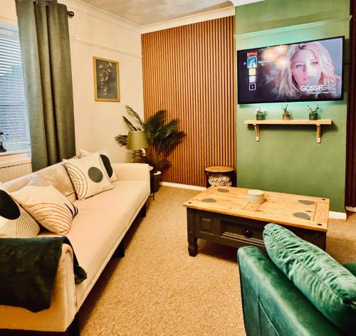 a living room with a couch and a table at Cherry Blossom Apartment - 3 bed, parking, garden in Norwich