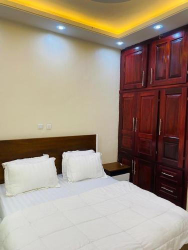 a bedroom with a large white bed with wooden cabinets at Labelle Elitestay in Buea