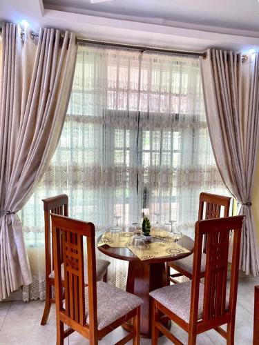 a dining room with a table and chairs in front of a window at Labelle Elitestay in Buea