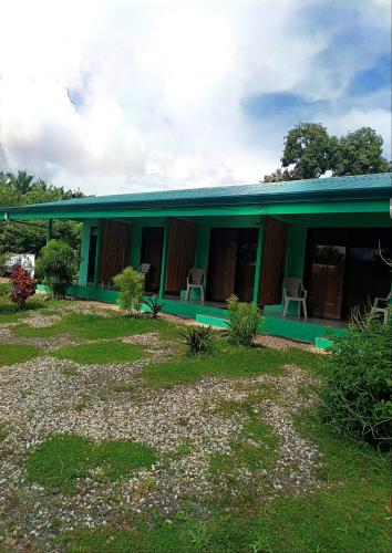 a green building with chairs in front of it at Macaw in Puerto Jiménez