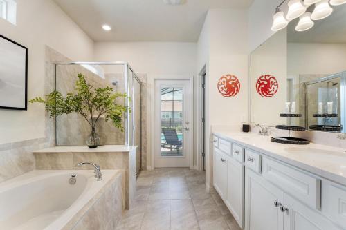 ein Badezimmer mit zwei Waschbecken und einer Badewanne und einem Spiegel in der Unterkunft Water Park, Game Room, Magical Design, Great Location in Davenport