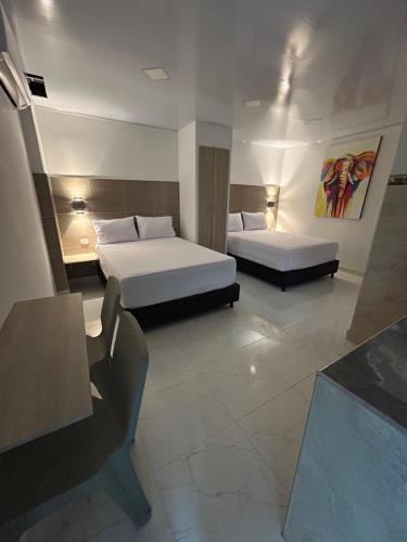 a hotel room with two beds and a table and chairs at Hotel Brisas del Mar in Santa Marta