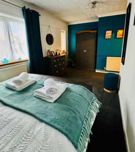 a bedroom with blue walls and a bed with towels on it at Cherry Blossom Apartment - 3 bed, parking, garden in Norwich
