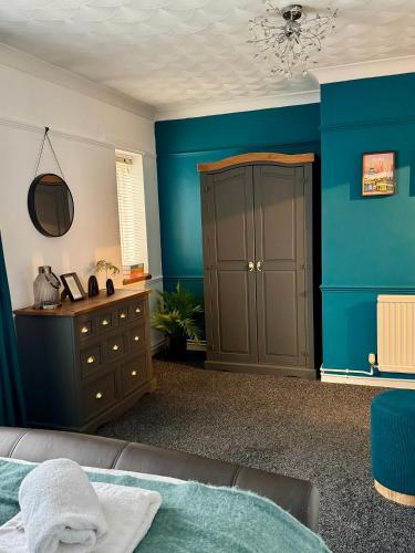 a bedroom with blue walls and a bed and a dresser at Cherry Blossom Apartment - 3 bed, parking, garden in Norwich