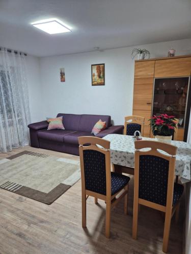 a living room with a table and a purple couch at Olgas Ferienwohnung Saarburg Bahnhofstraße 13 G in Saarburg