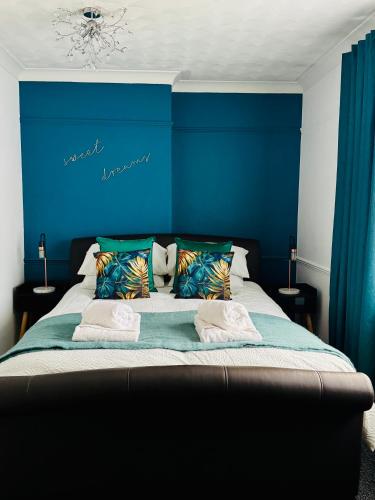 a bed with a blue head board with pillows at Cherry Blossom Apartment - 3 bed, parking, garden in Norwich
