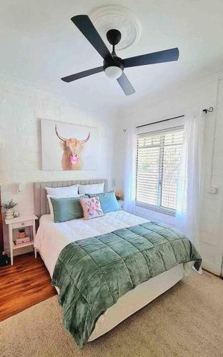 a bedroom with a bed with a ceiling fan at Bakery Cottage Moyhu in Moyhu