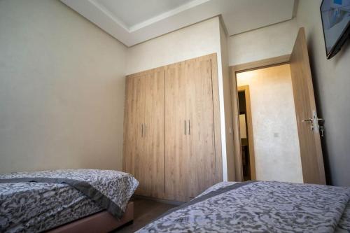 a bedroom with two beds and a wooden door at Cosy appartement 2 BR avec vue panoramique piscine in Aïn Harrouda