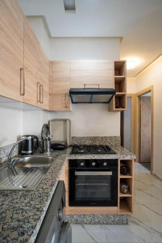a kitchen with a sink and a stove top oven at Cosy appartement 2 BR avec vue panoramique piscine in Aïn Harrouda