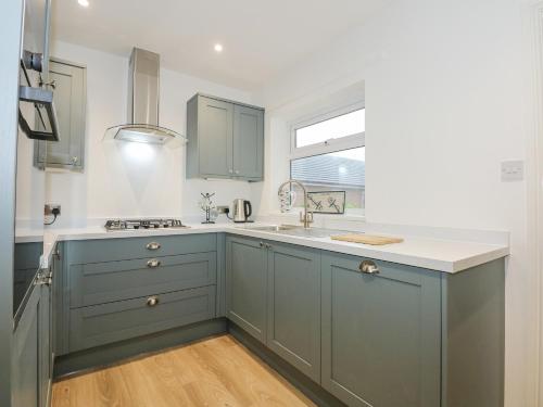 a kitchen with blue cabinets and a window at Seagull Cottage in Holyhead