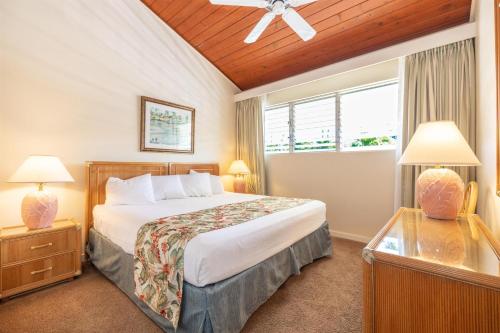 a bedroom with a bed and two lamps and a window at Napili Sunset Beach Front Resort in Lahaina