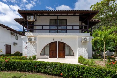 a white house with a brown door at Fuego del Sol Beachfront Hotel in Jacó