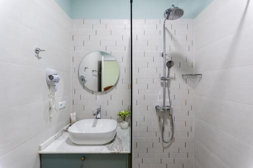 a white bathroom with a sink and a mirror at Central Inn in Kutaisi