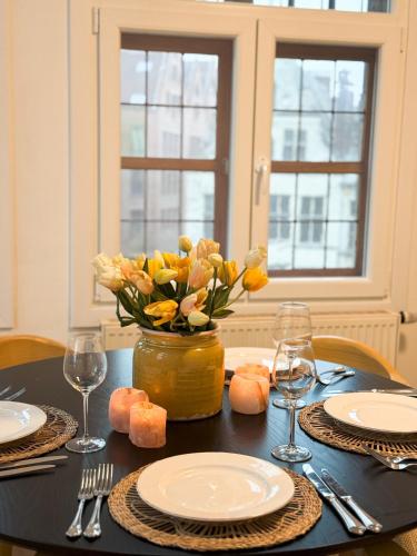 a table with plates and a vase of flowers on it at Le FauBourg Suites in Antwerp