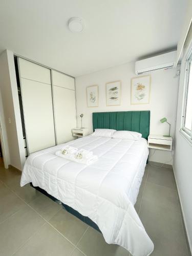a white bed with a green headboard in a bedroom at Saavedra 118 8D by depptö in Bahía Blanca
