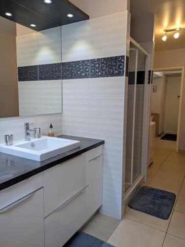 une salle de bain blanche avec un lavabo et un miroir dans l'établissement Appartement 6 pers, centre-ville- T3, 90m2, à Briançon