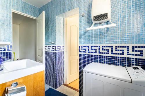 La salle de bains est pourvue de carrelage bleu et d'un lave-linge. dans l'établissement Petite maison avec terrasse - Soleil et Jardin, aux Arcs-sur-Argens