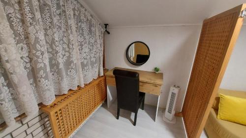Zimmer mit einem Schreibtisch, einem Spiegel und einem Vorhang. in der Unterkunft Apartments Hamidović in Tuzla