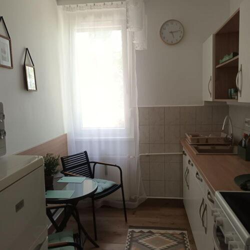 a kitchen with a table and a window with a clock at Kata Belvárosi Apartman in Veszprém