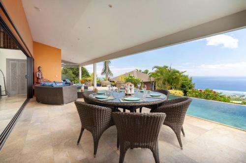 a dining room with a table and chairs and the ocean at Villa Ireina magnificent sea view in Punaauia