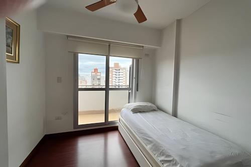 a bedroom with a bed and a large window at Moderno departamento zona centro in Rosario