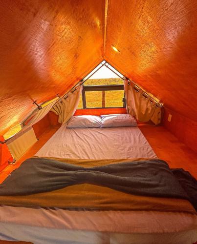 a small bed in a tent with a window at Chalé Henri Salvador na Vinícola Reconvexo in Morro do Chapéu