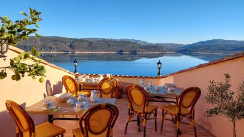a patio with tables and chairs and a view of a lake at chambres d'hôtes Les Fenières in Sainte-Croix-de-Verdon