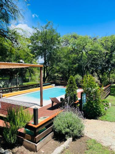 a swimming pool in a yard with a wooden deck at Cabañas La Frontera in Villa General Belgrano