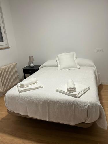a white bed with two utensils on top of it at Mercado Chico SUITES in Avila