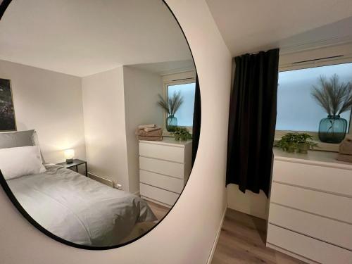 a mirror in a bedroom with a bed and a window at Polar - TAG-apartments in Tromsø