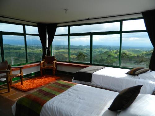 Sierra Morena Eco Hotel في فيلانديا: سريرين في غرفة مع نوافذ كبيرة