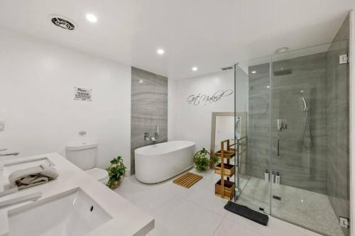 a white bathroom with a tub and a shower at Pompano Cove in Pompano Beach