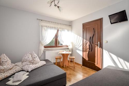 a bedroom with a couch and a table and a window at Marysieńka Pokoje Hrube Wyżne 12A in Zakopane