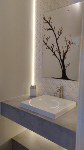 a bathroom with a white sink and a mirror at Suítes Garden in Pomerode