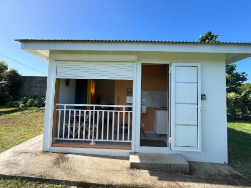 a small house with a porch and a balcony at Bungalow à baie-Mahault in Baie-Mahault