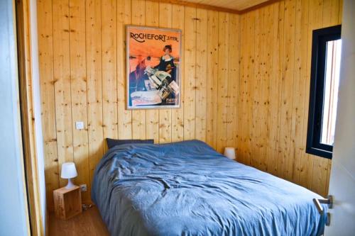 - une chambre avec un lit et une affiche murale dans l'établissement Maison en Bois 6 pers - Plage&Forêt Montalivet Vensac-Océan, à Vensac