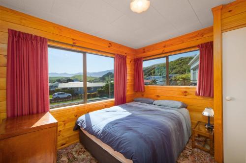 カイコウラにあるA Classic Kiwi Bach in South Bayのベッドと大きな窓のある寝室