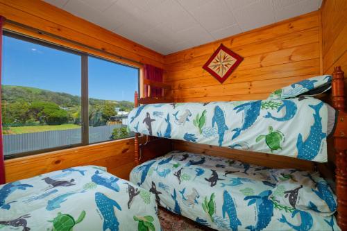 two beds in a room with a window at A Classic Kiwi Bach in South Bay in Kaikoura