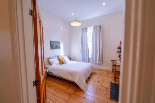 a bedroom with a bed with white sheets and a window at Signal Cottage close to beach and Semaphore Road in Semaphore
