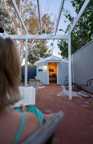a woman sitting on a bench reading a book at Signal Cottage close to beach and Semaphore Road in Semaphore