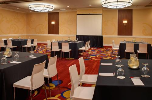 a conference room with tables and chairs and a screen at Wyndham Cleveland Airport in Cleveland