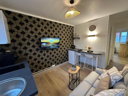 un salon avec un canapé et une télévision sur un mur dans l'établissement LeRelaisdOdile - Studio Confort - Proche Hôpital - Idéal Couple & Travailleur- Accès Autoroute Rapide, à Valenciennes