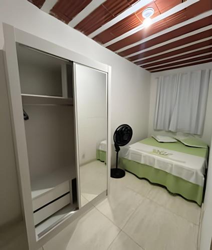 a small bedroom with a bed and a mirror at Bela casa 3 quartos perto do Buritis in Belo Horizonte