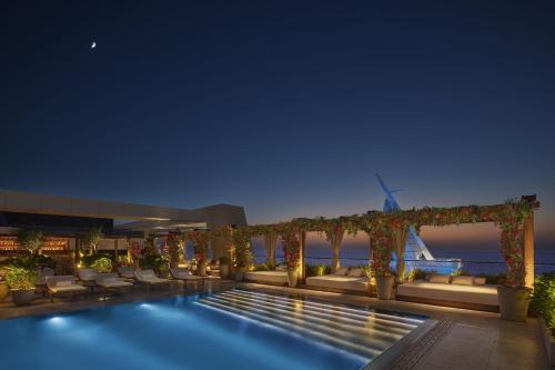 a hotel swimming pool at night with a pergola at The Jeddah EDITION in Jeddah